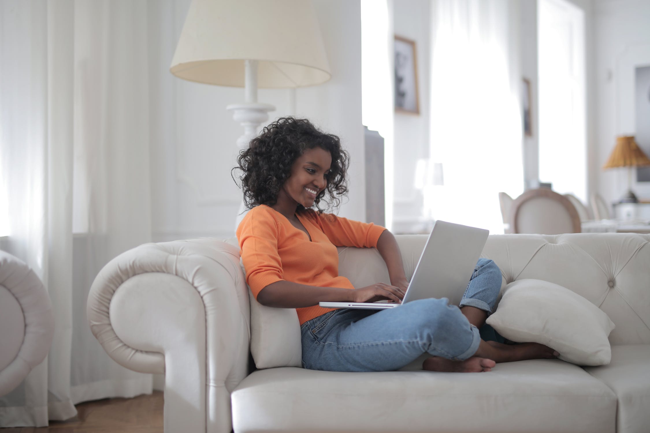 Woman Sitting on White Couch Using Laptop Computer